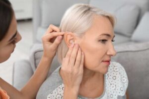 A doctor fits a hearing aid into a woman's ear