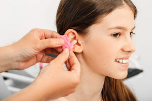 Picture of an audiologist creating custom hearing protection for a teenage girl.